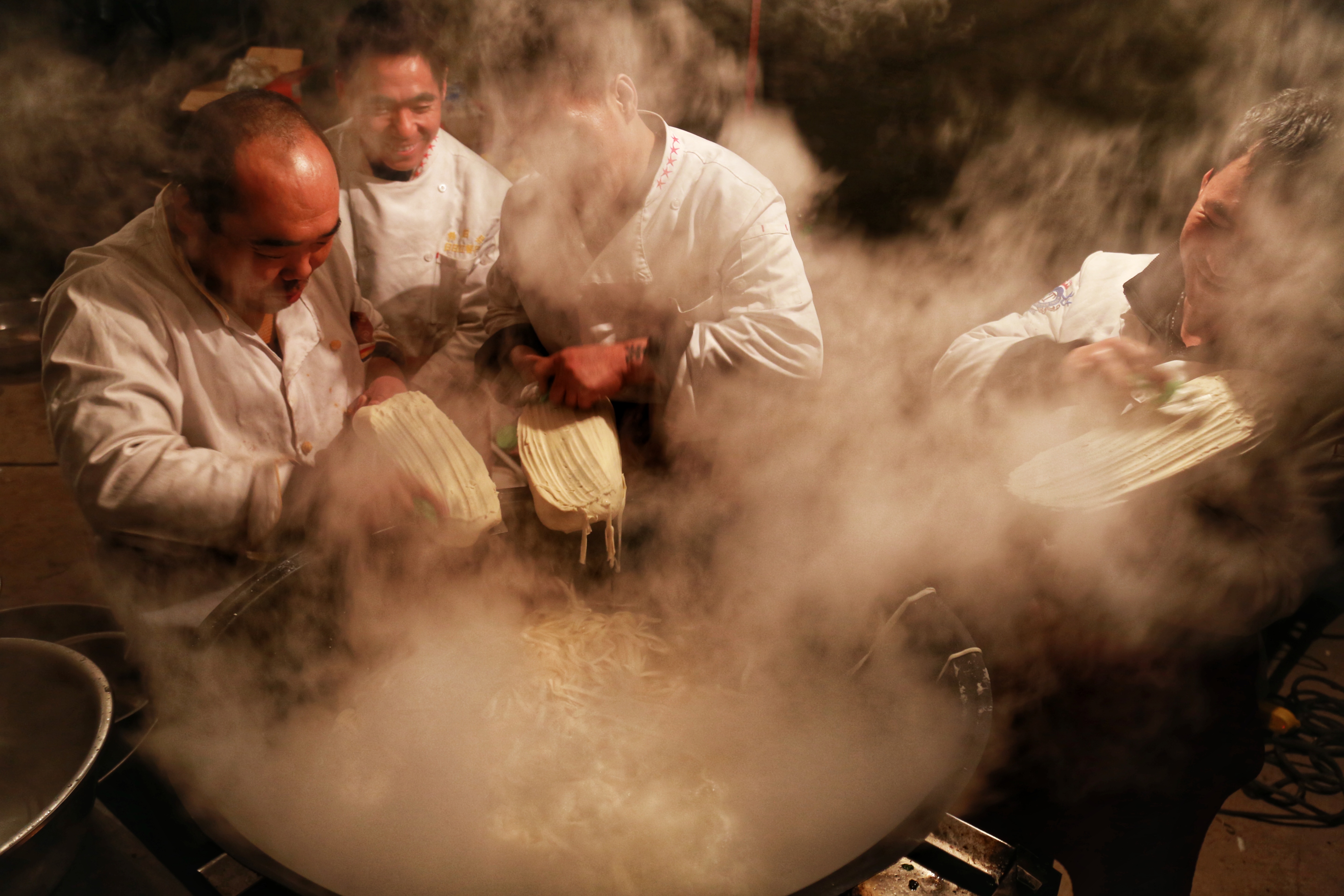 山西太原小返村,几个师傅围着一口冒着热气的大锅在做刀削面,招待来客